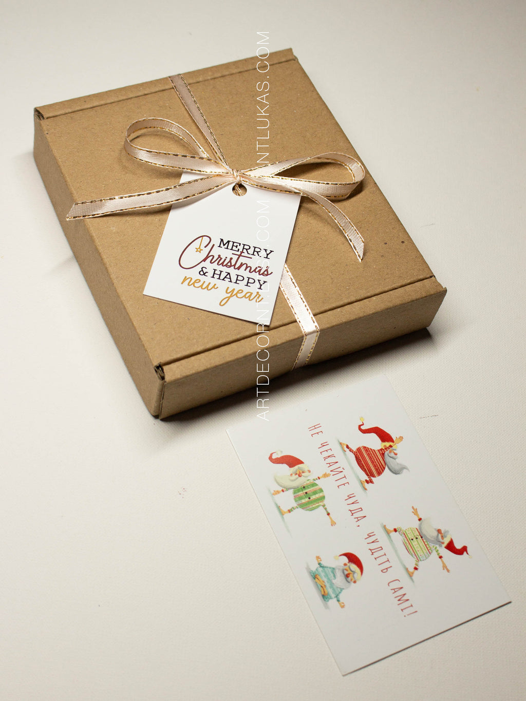 Gift box with a decorative bow and 'Merry Christmas & Happy New Year' tag, accompanied by a small card with cartoon characters.